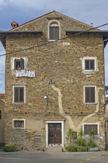Woman in old house hanging clothes on washing line in the city Koper