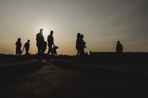 Silhouettes of walkers stand out against the setting sun on the harbour promenade in Oslo