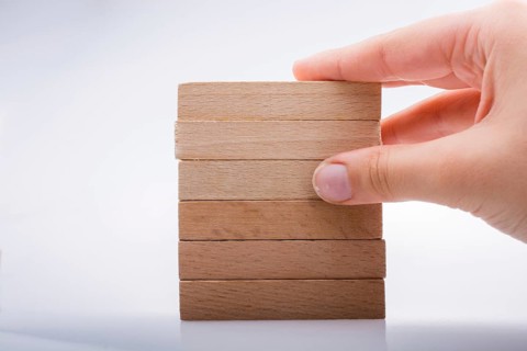 Hand holding wooden domino on a white background