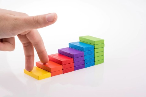 Hand playing with colored domino on white background
