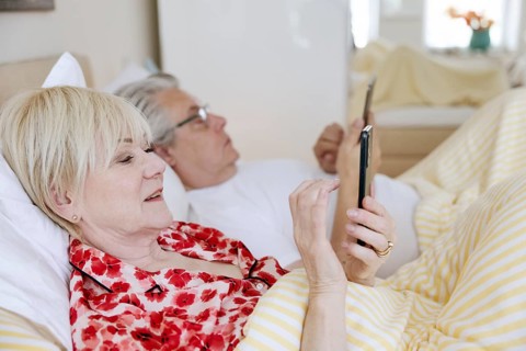 Elderly couple lying in bed together in their bedroom
