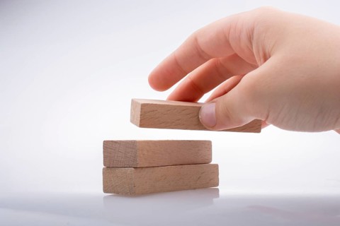 Hand holding wooden domino on a white background