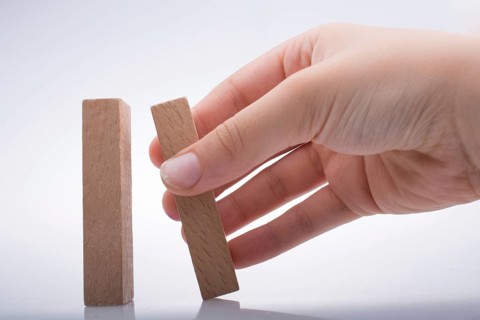 Hand holding wooden domino on a white background