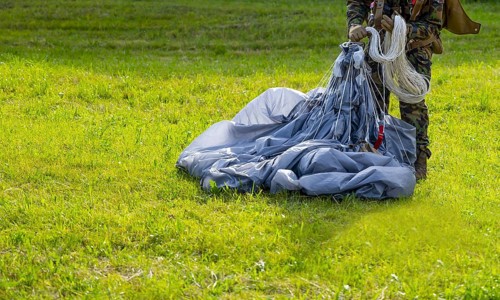 Military Parachuter Standing on the Grass with His Parachute in Switzerland