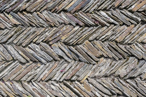 Slate slabs stacked in a herringbone pattern to form a wall