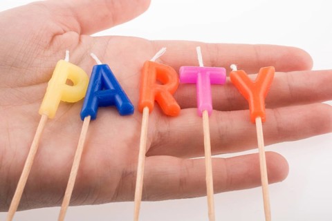 Color candles in hand on sticks write the word party