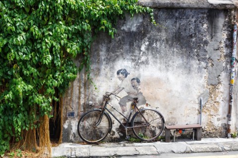 Street art boy and girl on bicycle on a wall in George Town on Penang Island