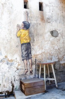 Street art Reaching Up on a wall in George Town on Penang Island