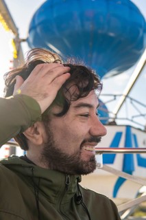 Very excited emotional portrait of a young latin man in the cabin of a ferris wheel. Amusement park adventures and fear of heights