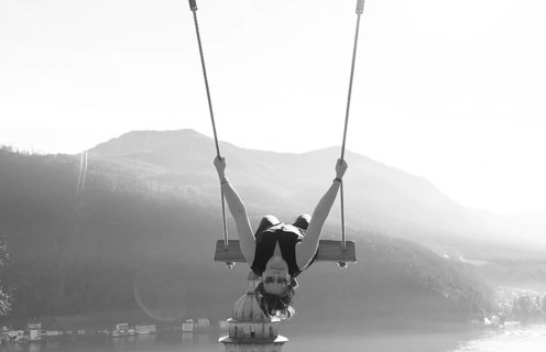 Woman on a Swing with Mountain View and Sunlight over Lake Lugano in Morcote