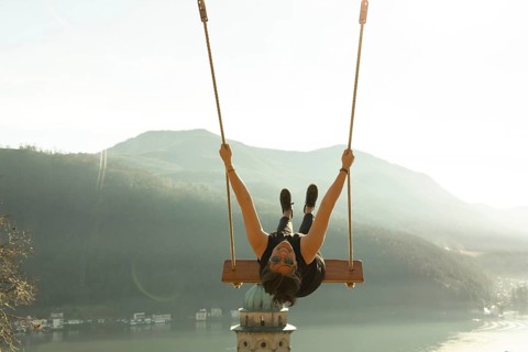 Woman on a Swing with Mountain View and Sunlight over Lake Lugano in Morcote