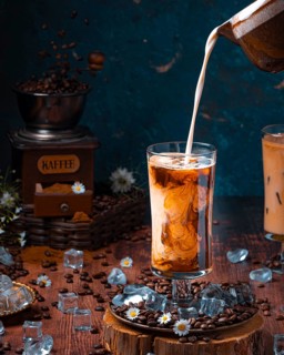 Milk is poured into glass with cold coffee