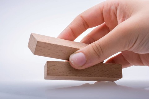 Hand holding wooden domino on a white background