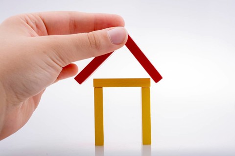Hand holding domino pieces forming a house shape