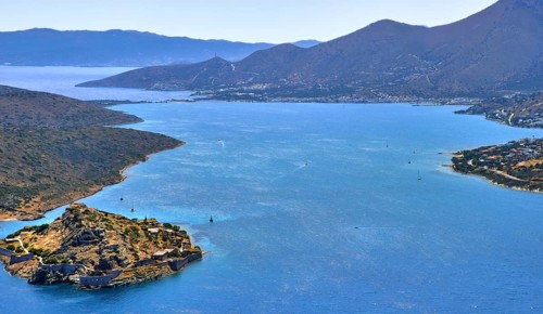 Aerial view of clear sea waters of harbor between Spinalonga island and peninsula