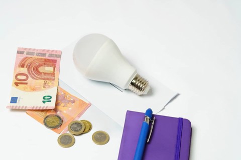 Light bulb on an electricity bill and banknotes and coins on a white background.concept of electricity price increase