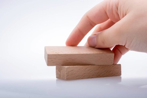 Hand holding wooden domino on a white background