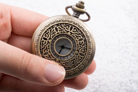 Retro style pocket watch in hand on white background