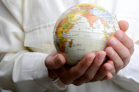 Child holding a small model globe in hand on white background