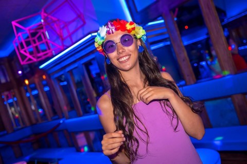 Brunette woman smiling at a night club party in purple glasses at a pub party