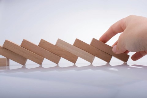 Hand holding wooden domino on a white background