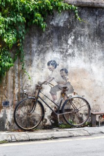 Street art boy and girl on bicycle on a wall in George Town on Penang Island
