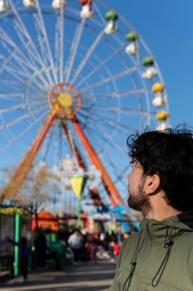 Portrait of latino man in an amusement park posing happy with the ferris wheel in the background