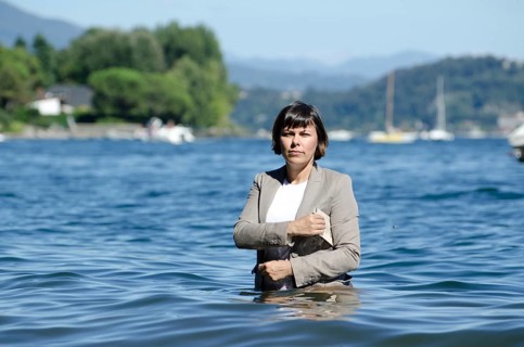 Elegant Business Woman with Suit Standing in the Water and Holding a Newspaper