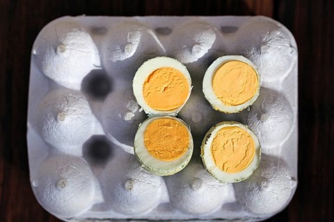 Cooked halved quail eggs on an egg carton