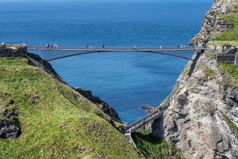 Tourists walk across the new footbridge to the peninsula with the castle ruins of Tintagel Castle