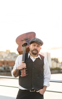 Portrait of a musician looking at camera while holding his guitar on his shoulder