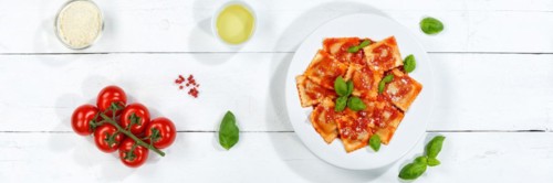Ravioli Italian pasta eat lunch dish with plate in tomato sauce from above on wooden board Panorama in Stuttgart