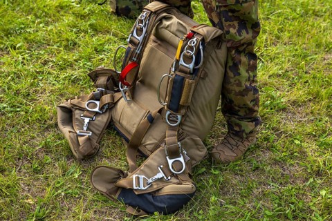 Military Parachuter Standing on the Grass with His Parachute in Switzerland