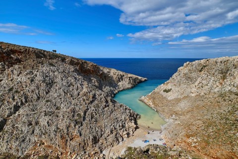 Beautiful view of z-shaped cove or lagoon in typical hills of Crete landscape. Clear blue sky and beautiful clouds on sunny day. Azure sea waters. Stefanou beach