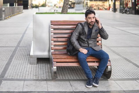 Latino businessman sitting on a bench talking on the phone