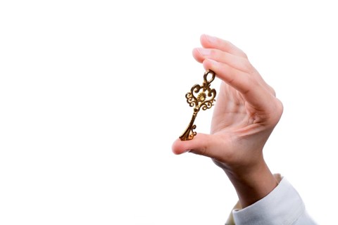 Hand holding a retro styled metal key on a white background