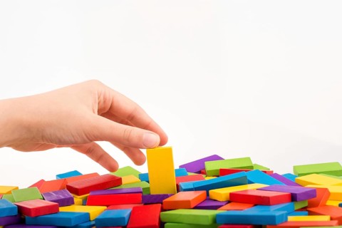 Hand playing with colored domino on white background