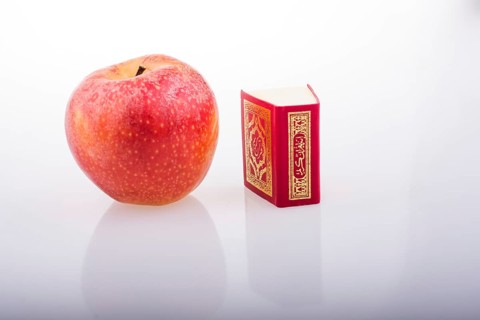 Red apple and Islamic Holy Book Quran in mini size