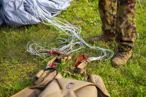 Military Parachuter Standing on the Grass with His Parachute in Switzerland