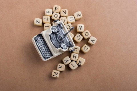 Letter cubes of made of wood around model typewritter