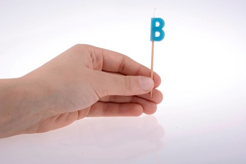 Color candle in hand on sticks writes the letter B