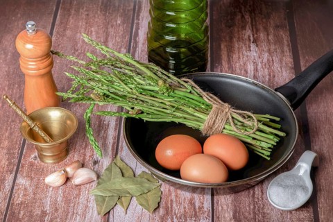 Bunch of wild asparagus in a frying pan with eggs