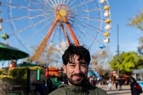 Portrait of latino man in an amusement park posing happy with the ferris wheel in the background