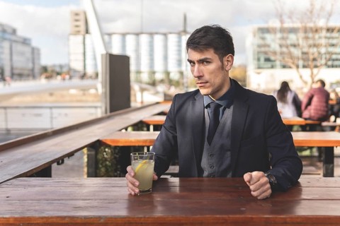 Businessman sitting at an outdoor bar drinking lemonade looking at the camera