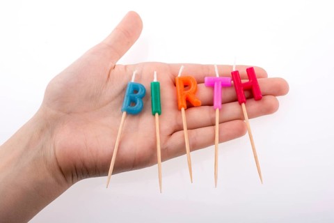 Color candles in hand on sticks write the word birth