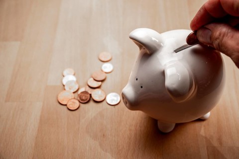 Male hand puts cent coin in piggy bank