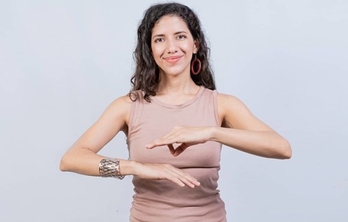 Smiling young woman gesturing in sign language. Female interpreter gesturing in sign language