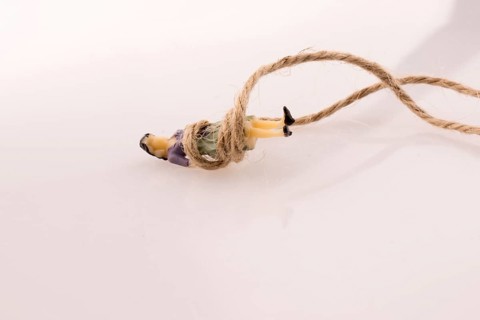 Woman figure lying down tied with a linen thread on a white background
