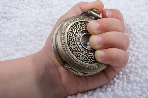 Retro style pocket watch in hand on white background