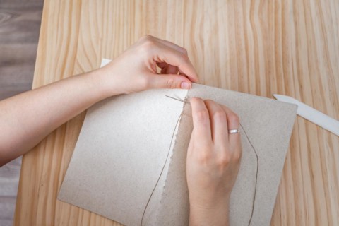 Close-up detail of woman's hands sewing a handmade notebook made in her workshop